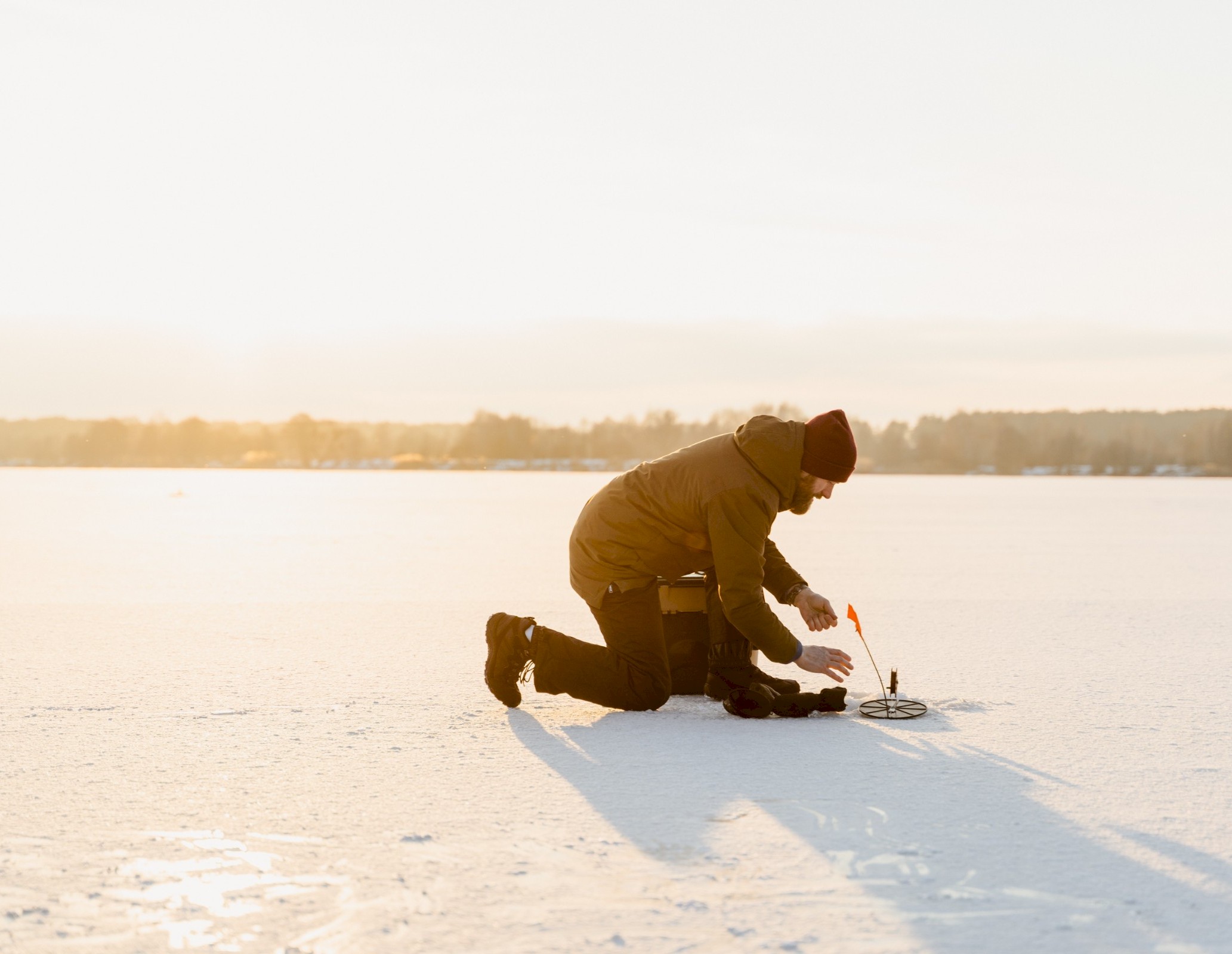A man ice fishing on the frozen lake