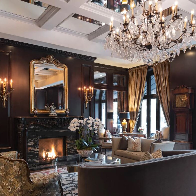 Un salon avec cheminée, grandes fenêtres et un chandelier